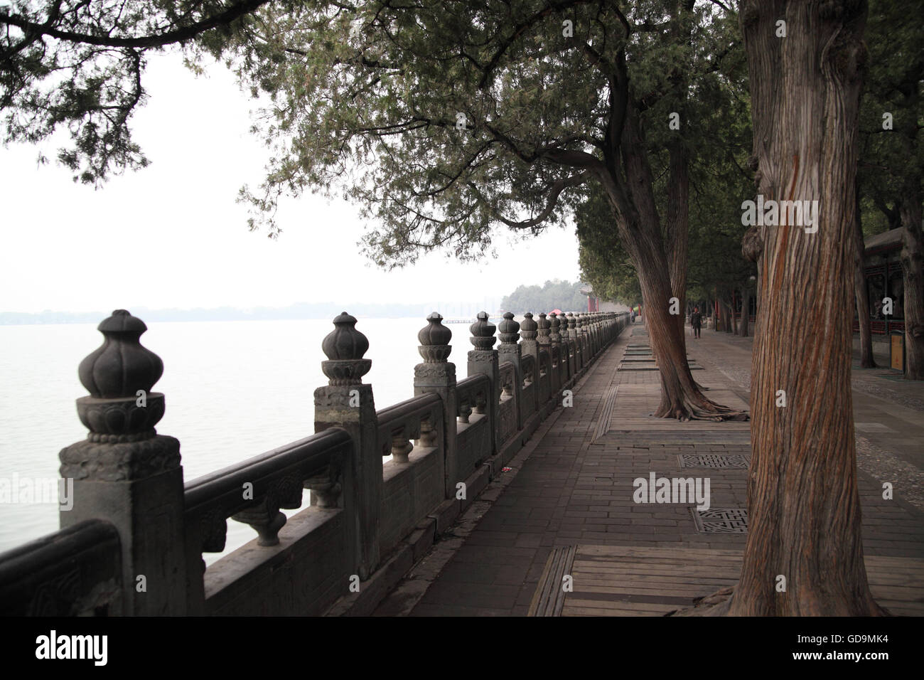 Trees and an architecturally ornamented fence along the Kunming Lake in the Imperial Summer Palace. Beijing, China. Stock Photo