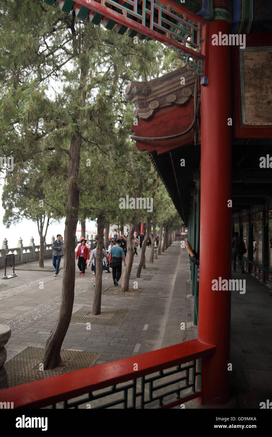 Tourists seen through a window in the Long Corridor as they walk along the promenade and the ornamented wall by the Kunming Lake in the Summer Palace. Stock Photo