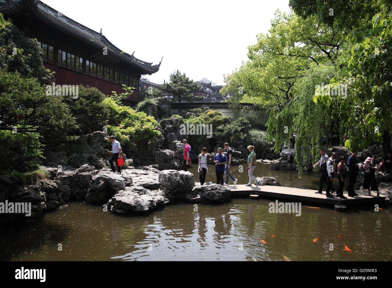 A house, a pond, gold fish, vegetation, a bridge and tourists in the 16th century  Yuyuan Garden, a typical classical garden. Stock Photo