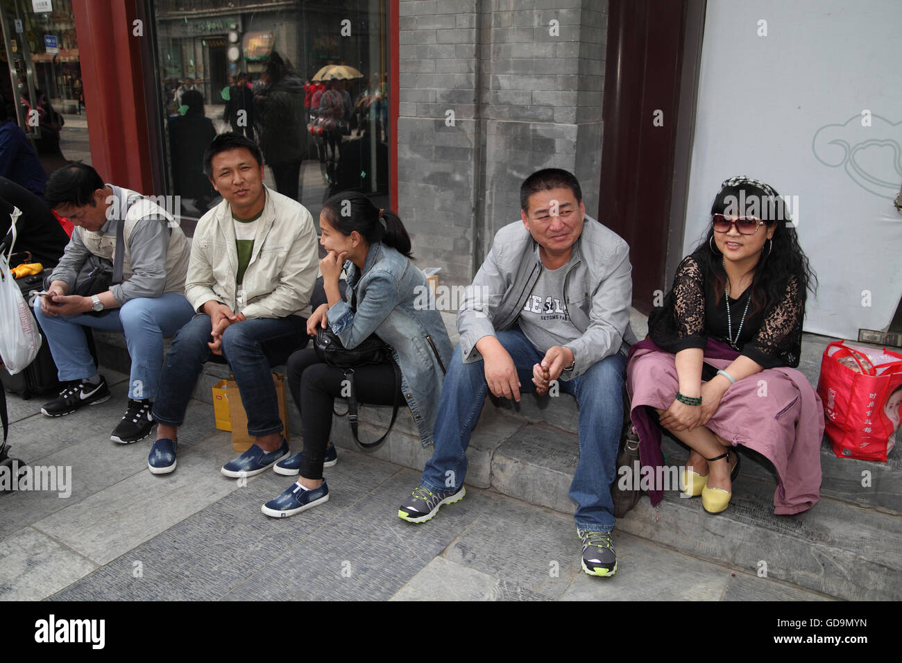Chinese people men and women sit on the sidewalk in front expensive