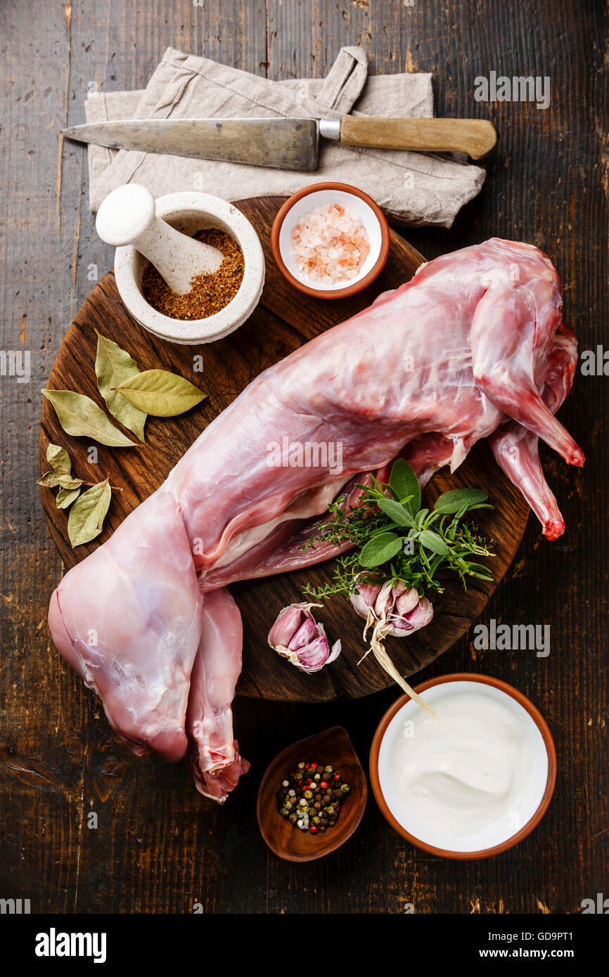 Raw whole rabbit and ingredients for cooking on dark wooden background Stock Photo