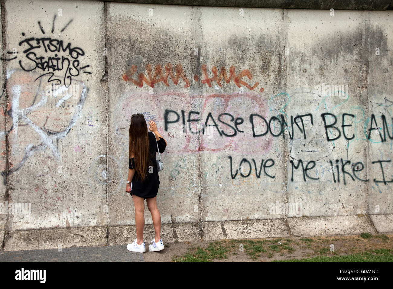 Girl is reading a message at the Section of original Berlin Wall at Bernauer Strasse in Berlin Germany Stock Photo