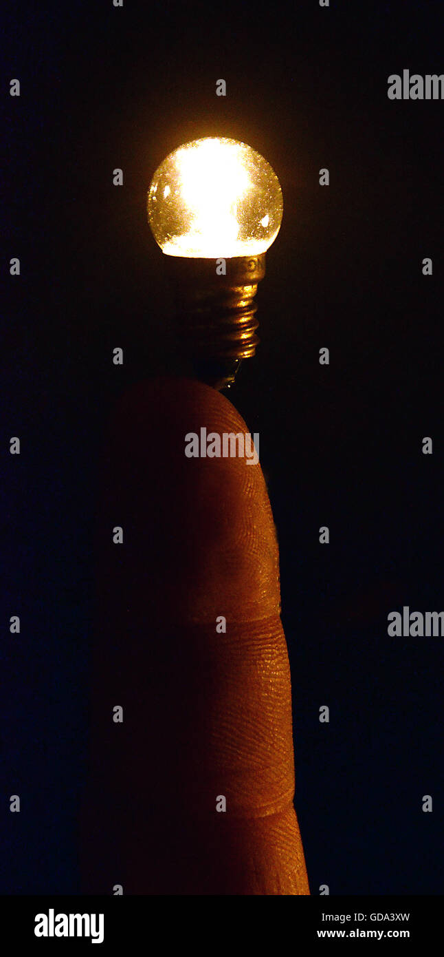 A light bulb seems to balance on a human finger. Stock Photo