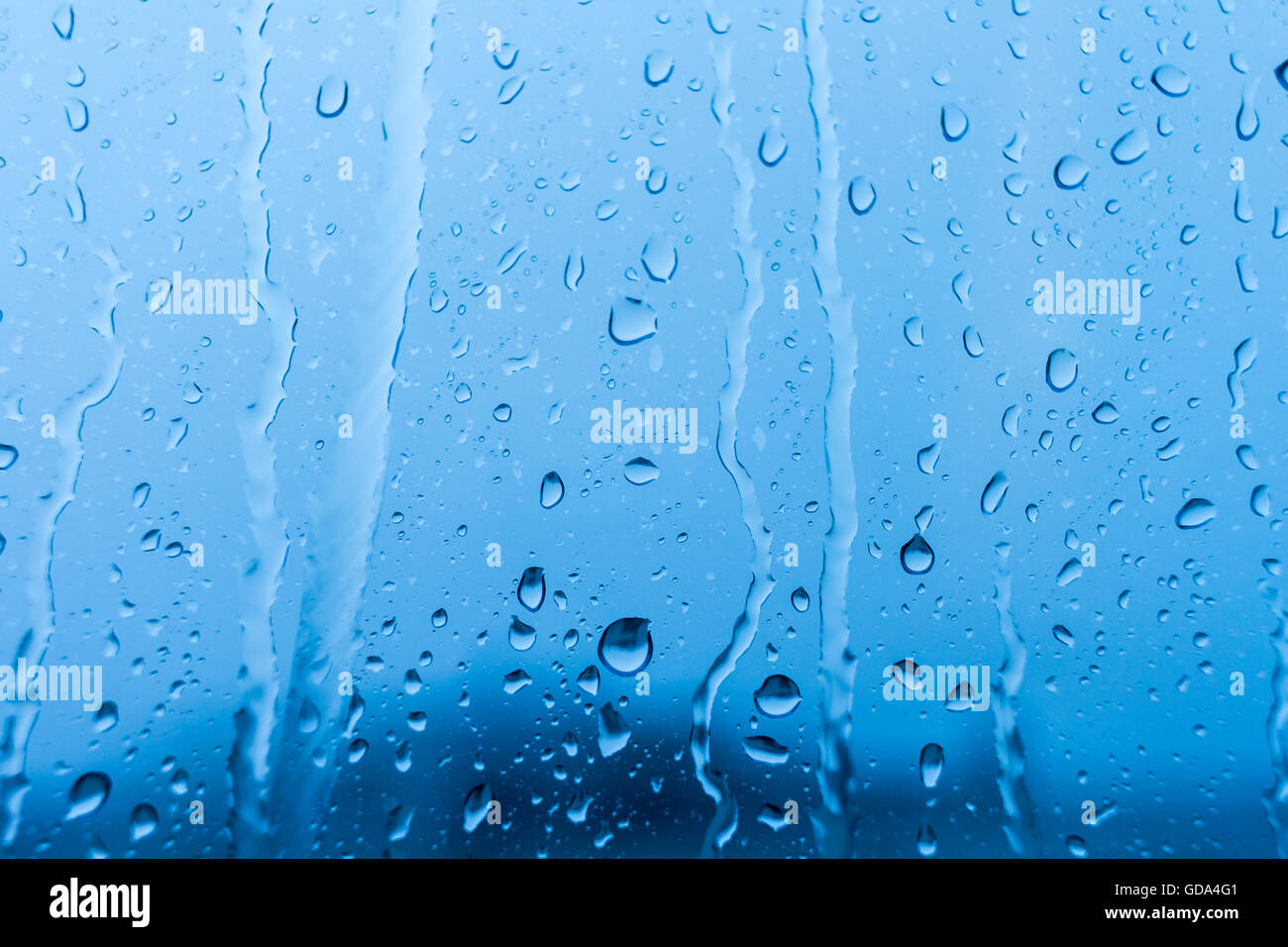 Drops of rain on blue glass background Stock Photo - Alamy