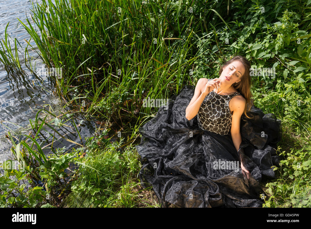 Young female model (20's) on photo shoot by river, Colnbrook, Berkshire, England, United Kingdom Stock Photo