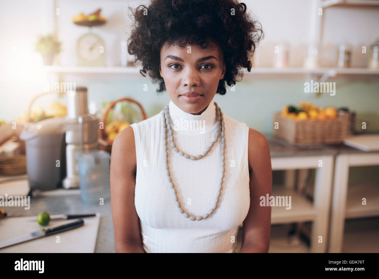 Closeup portrait of young african woman standing at juice bar. Attractive female looking at camera. Stock Photo