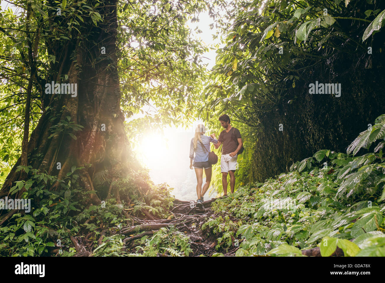 Young man and woman hiking in tropical jungle. Couple of hikers walking