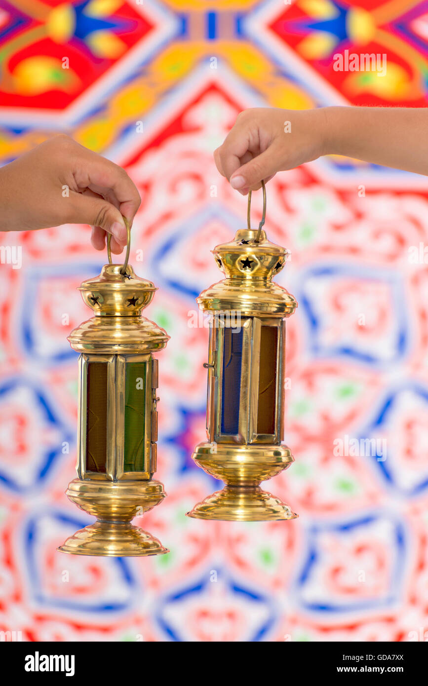 Hands with Ramadan Lantern over Ramadan Fabric Stock Photo