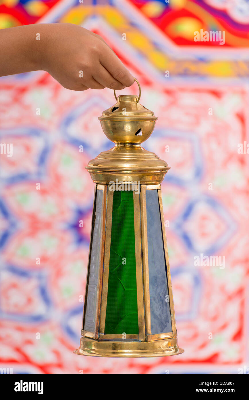 Hand with Big Ramadan Lantern over Ramadan Fabric Stock Photo