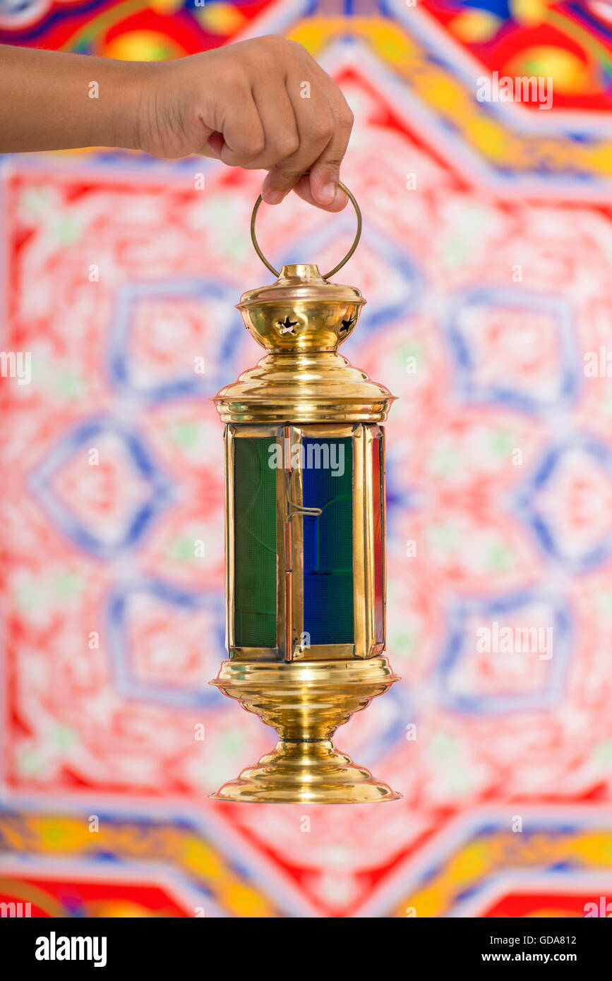 A Hand with Ramadan Lantern over Ramadan Fabric Stock Photo