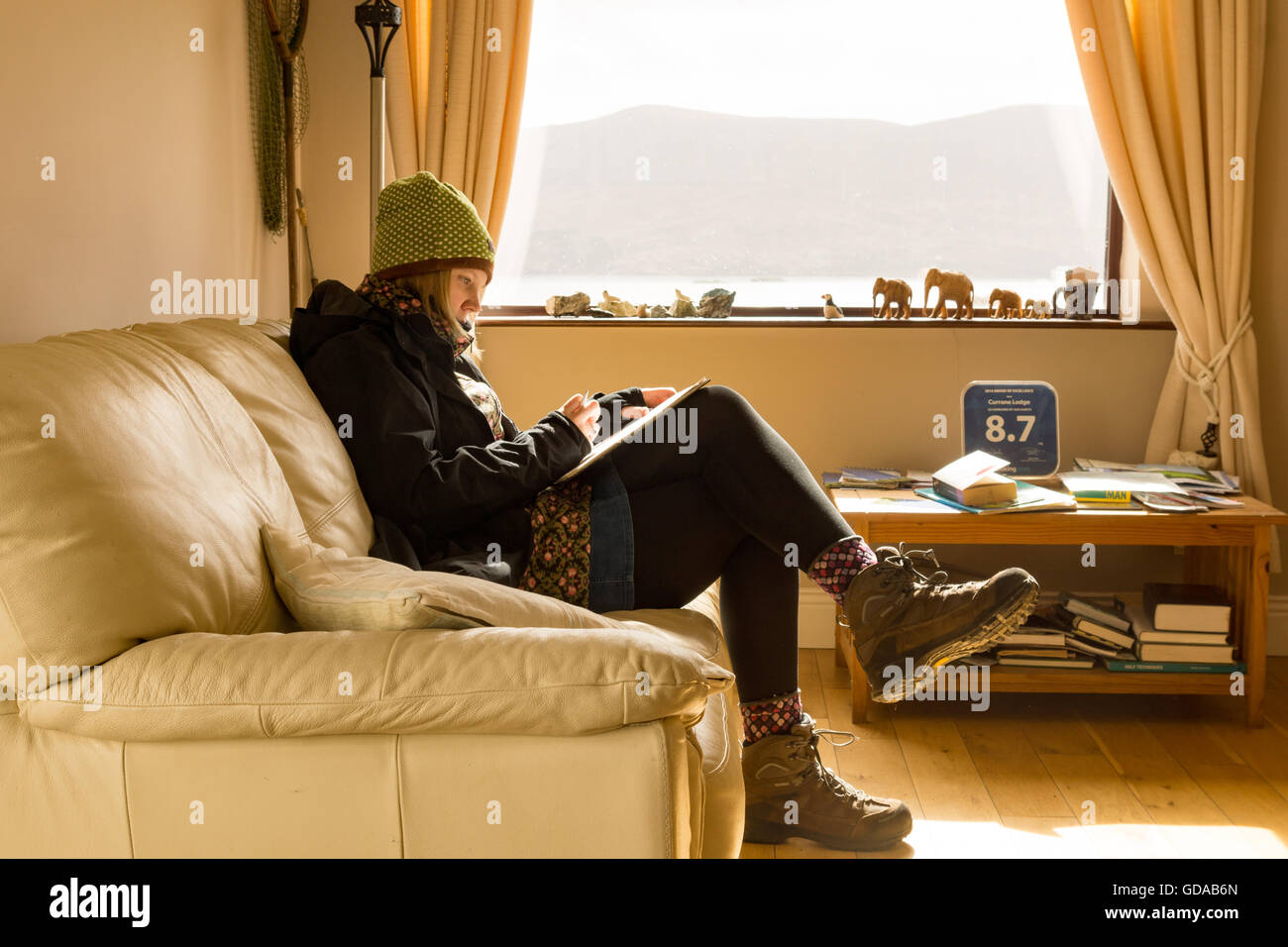 Ireland, Kerry, County Kerry, Accommodation at Lough Currane, Lake, Woman with warm clothes in living room Stock Photo