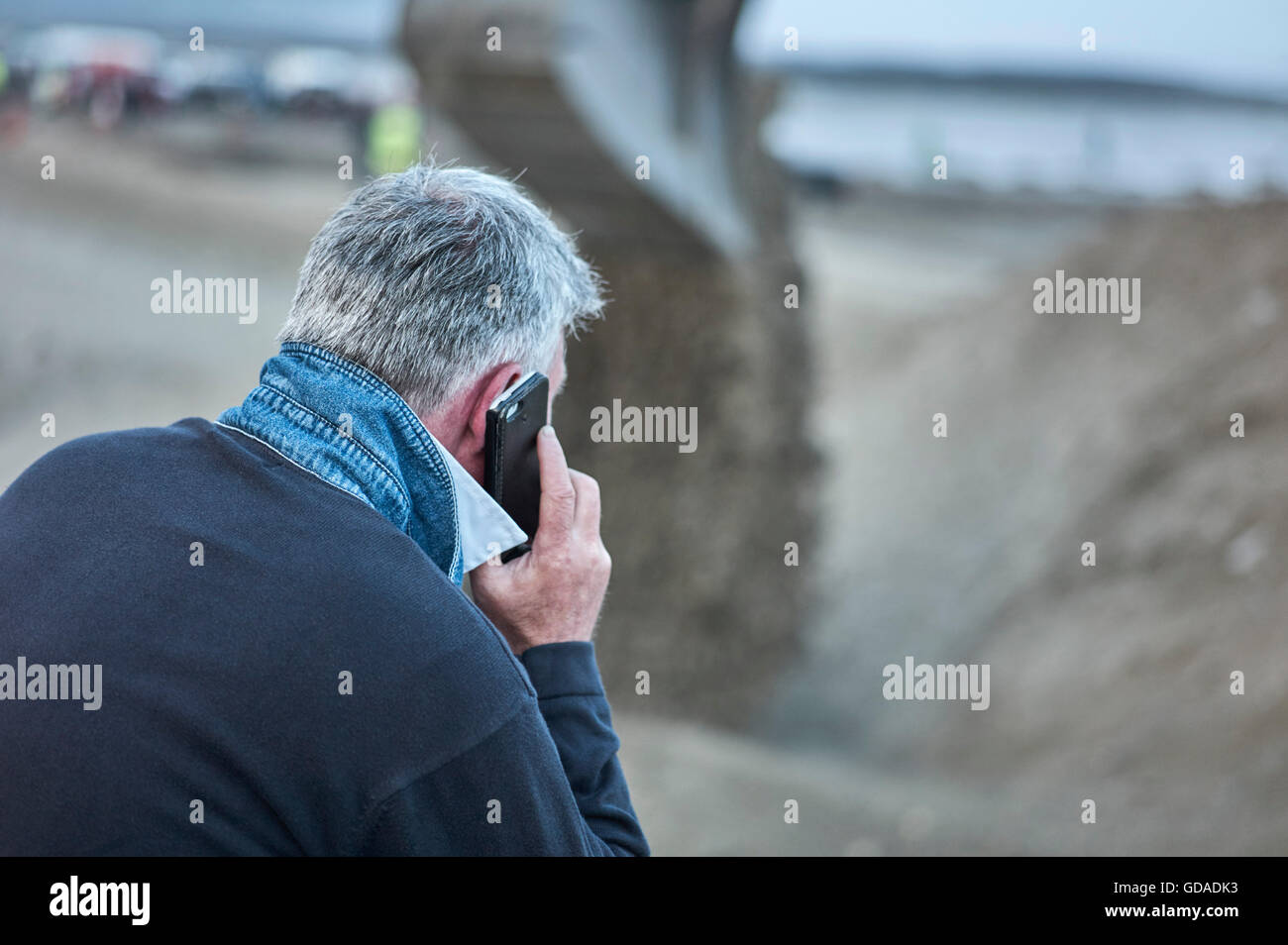 Grey haired man on mobile phone with blurred background Stock Photo