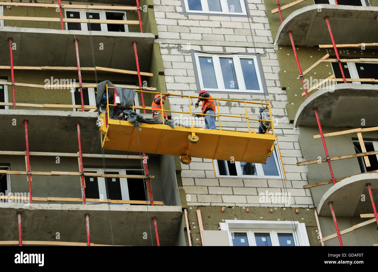 construction suspended cradle with workers on a newly built highrise