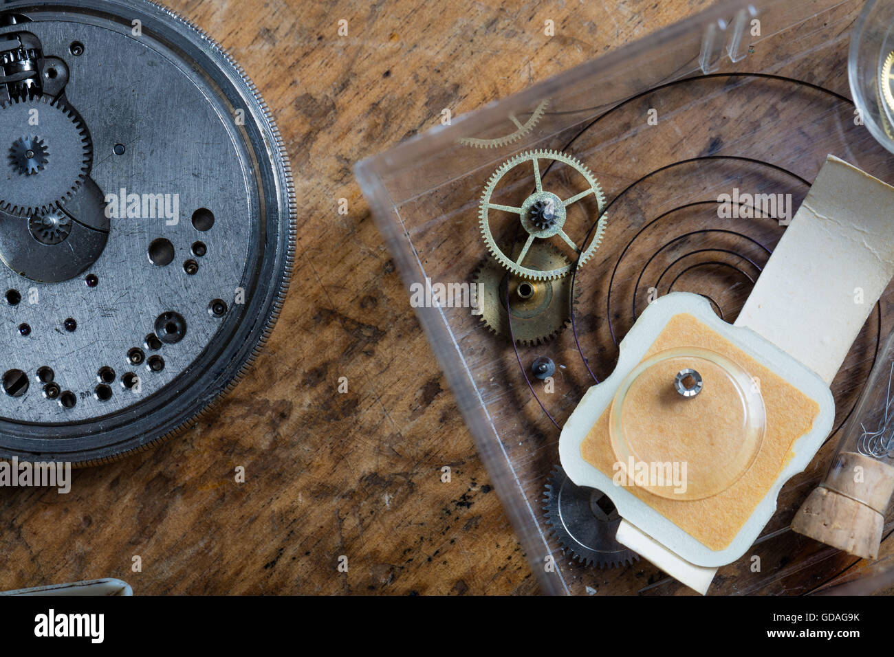 Components of a clock on a watchmakers workbench with a coiled spring ...