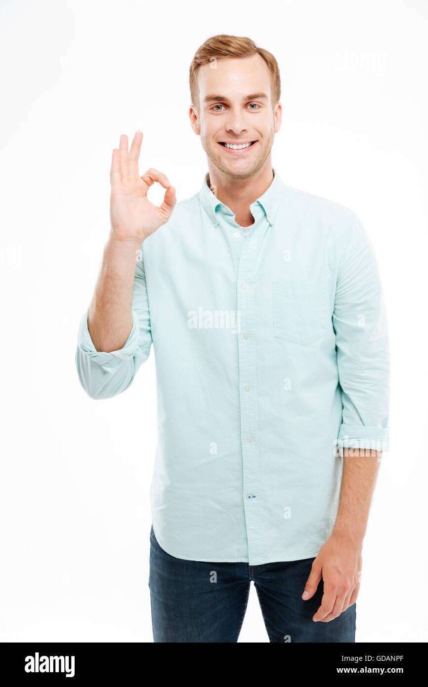 Happy young attractive man showing ok sign with fingers over white ...