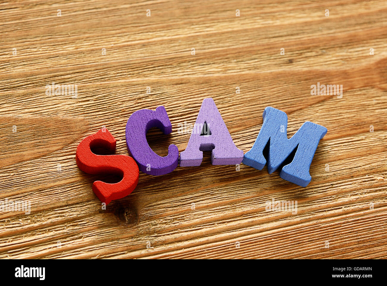 SCAM - words  made from multicolored   letters on wooden  background Stock Photo