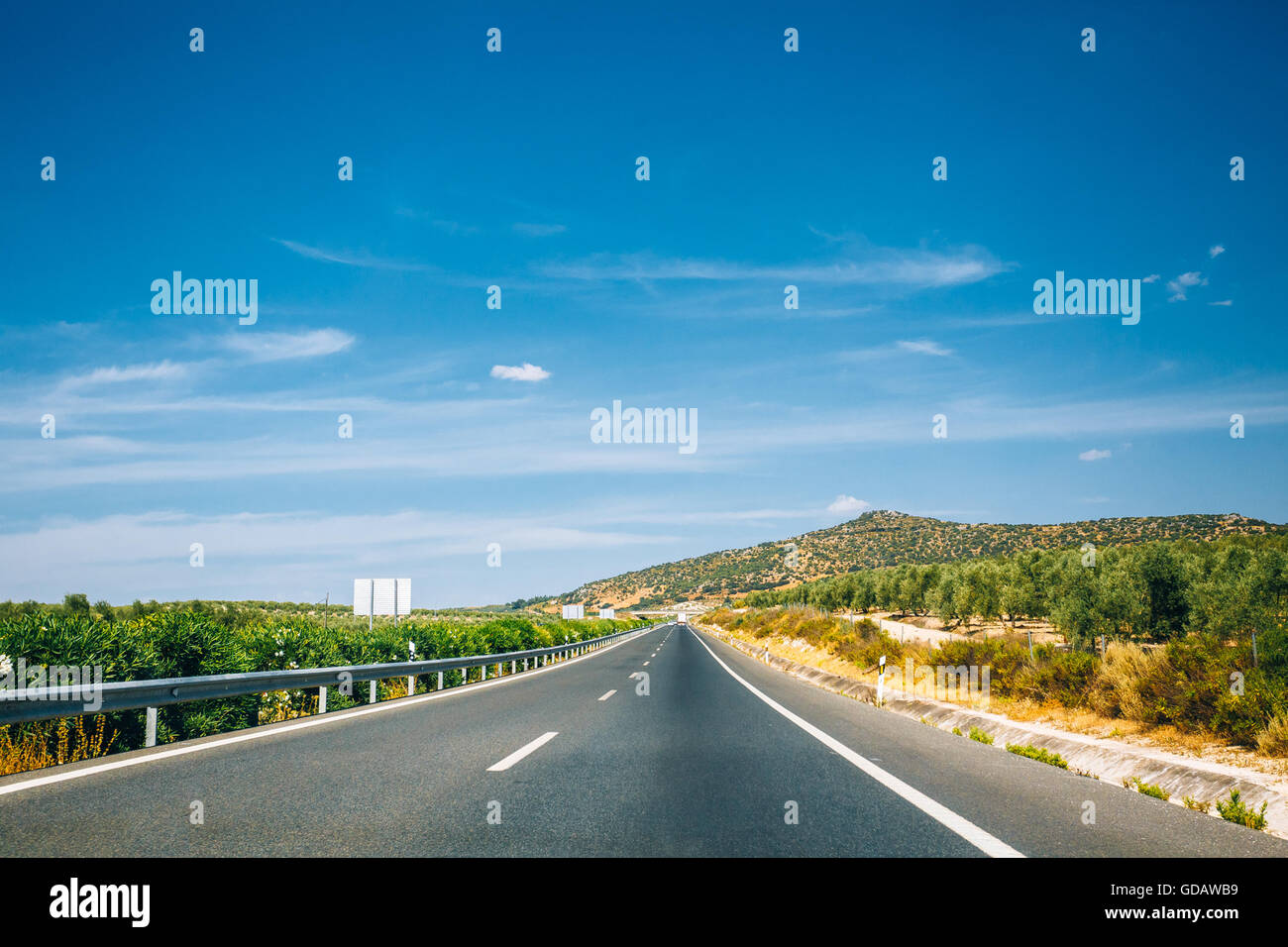Beautiful asphalt freeway, motorway, highway against the background of southern Spanish landscape. Travel road concept. Andalusi Stock Photo