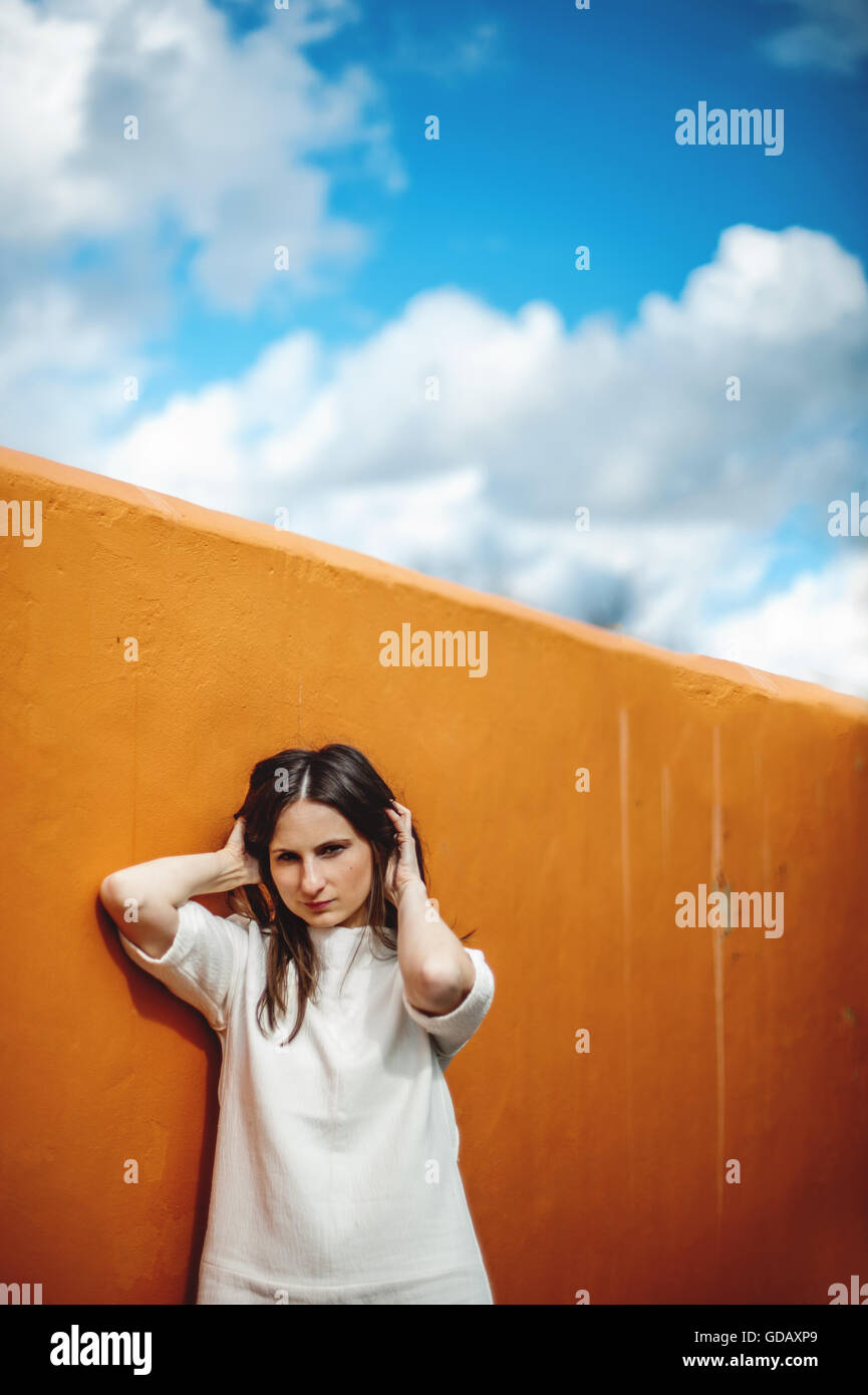young dark hair woman standing by yellow wall Stock Photo