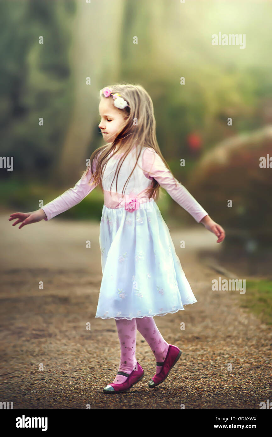 small girl with closed eyes dancing on the path in park Stock Photo