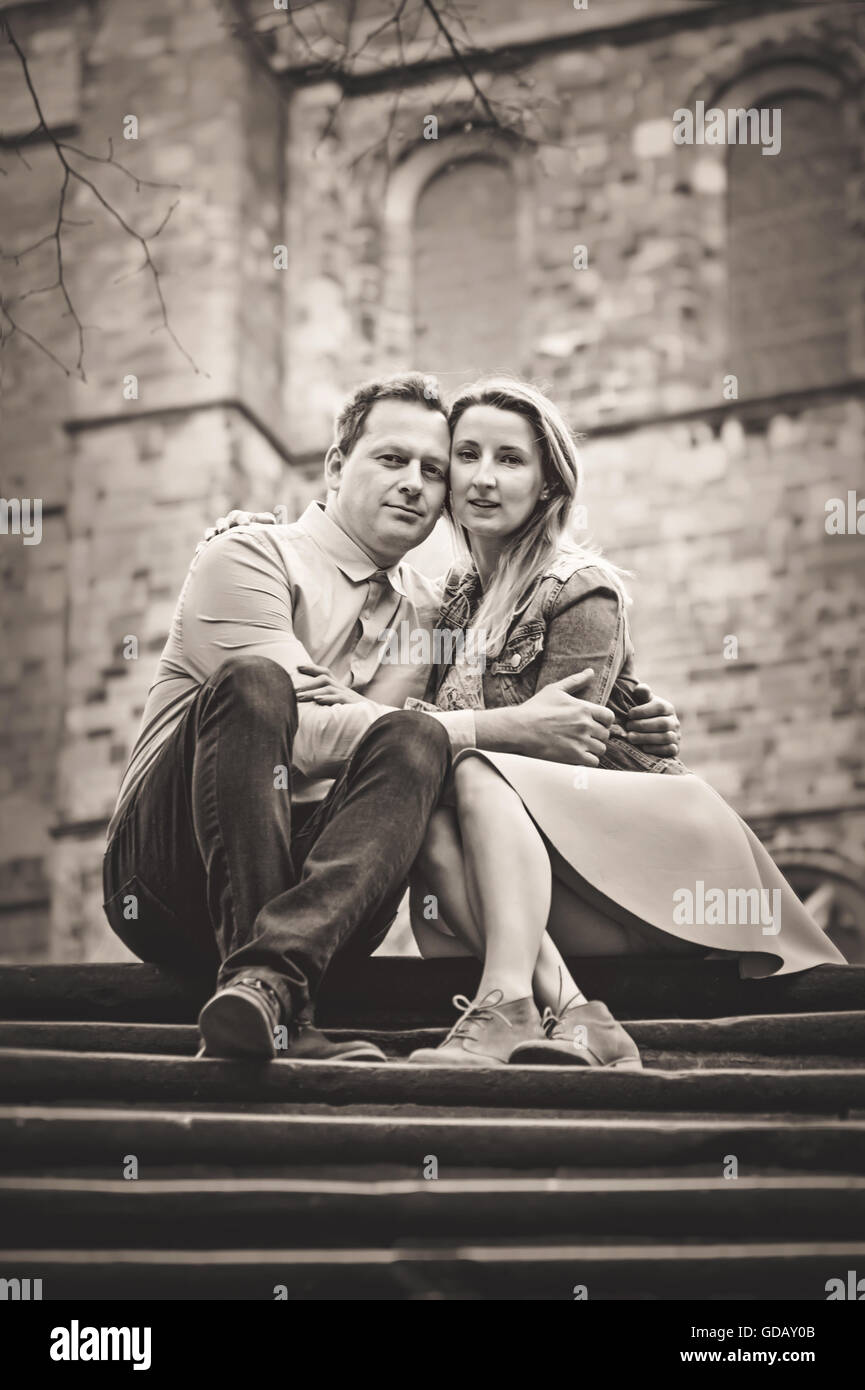 young couple sitting on stairs holding each other with love Stock Photo