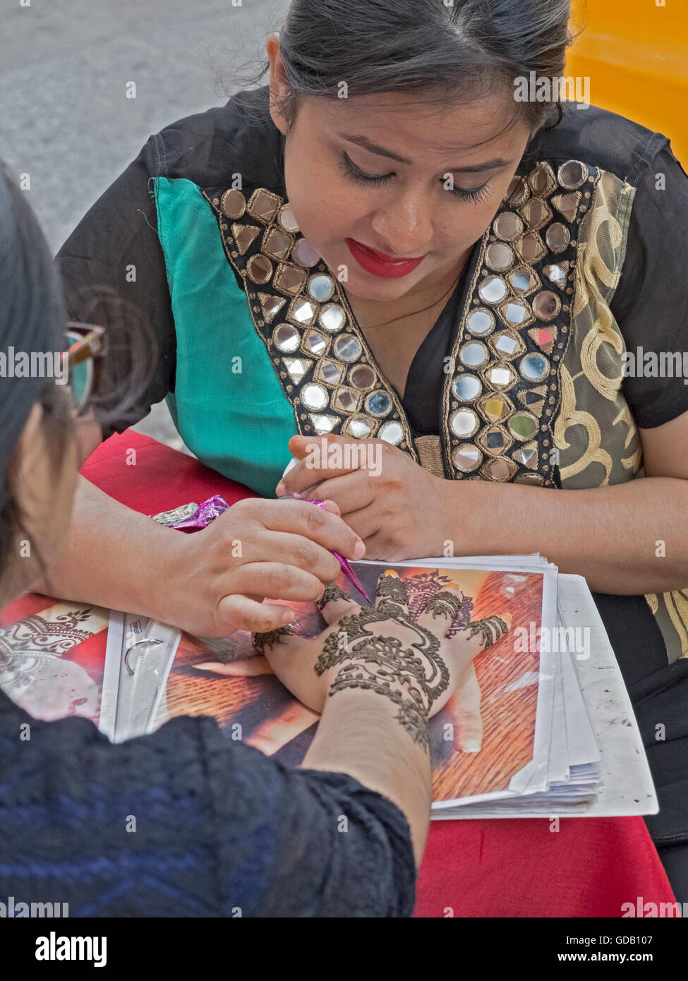 A woman from Bangladesh decorates a woman's hand with henna for the Eid al_Fitr festival. In Jackson Heights, Queens, New York. Stock Photo