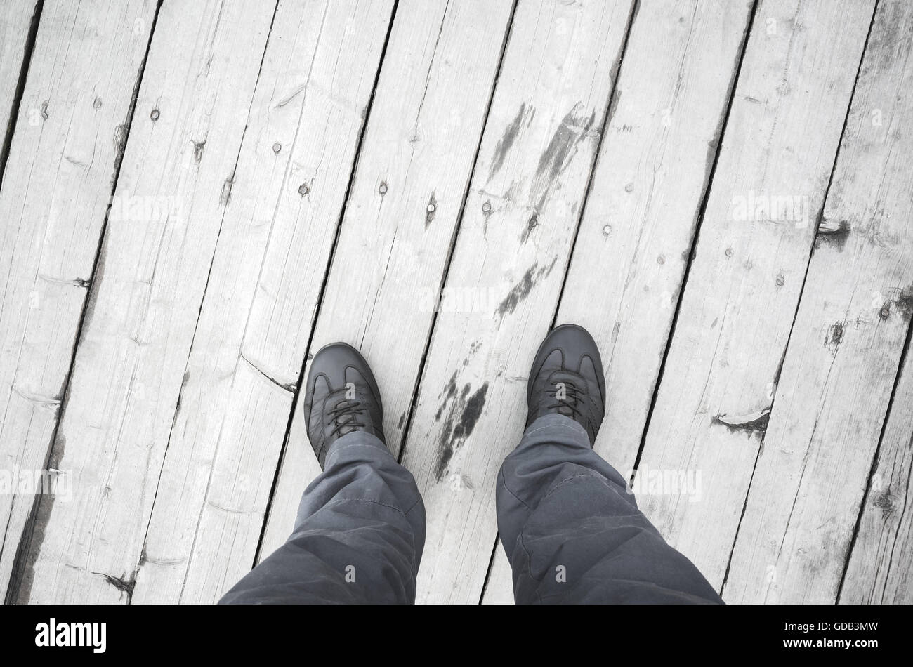 Male feet in leather shoes stand on white wooden pier floor, first person view Stock Photo