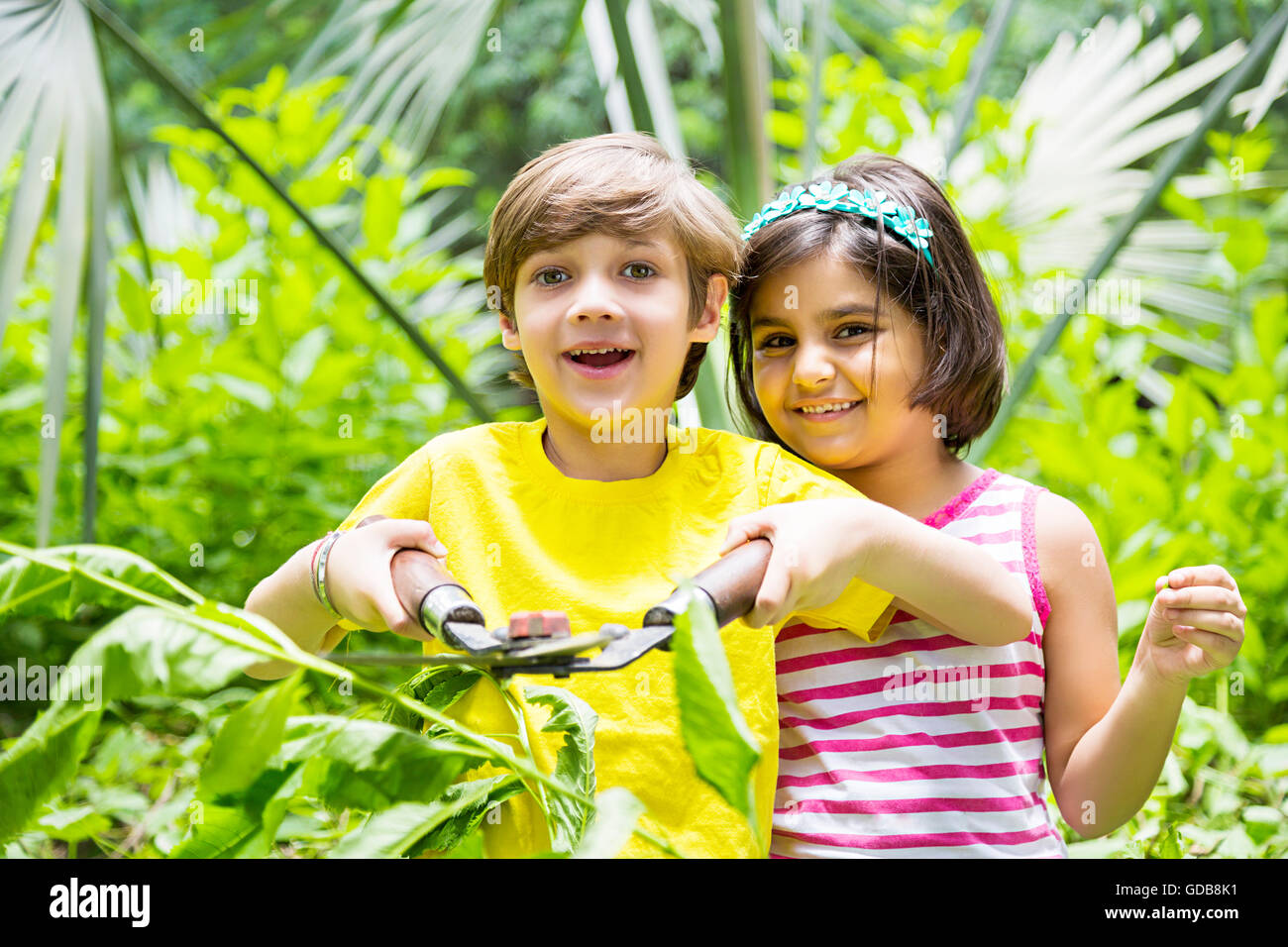 2 indian Kids girl and boy Friends park Scissors Cutting Plant Stock Photo