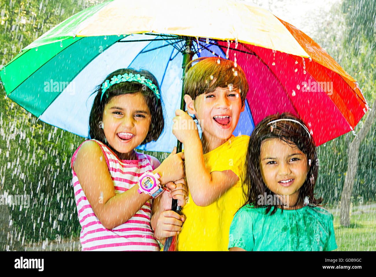 3 indians Kids friends park Rain Umbrella Rain Protection Stock Photo