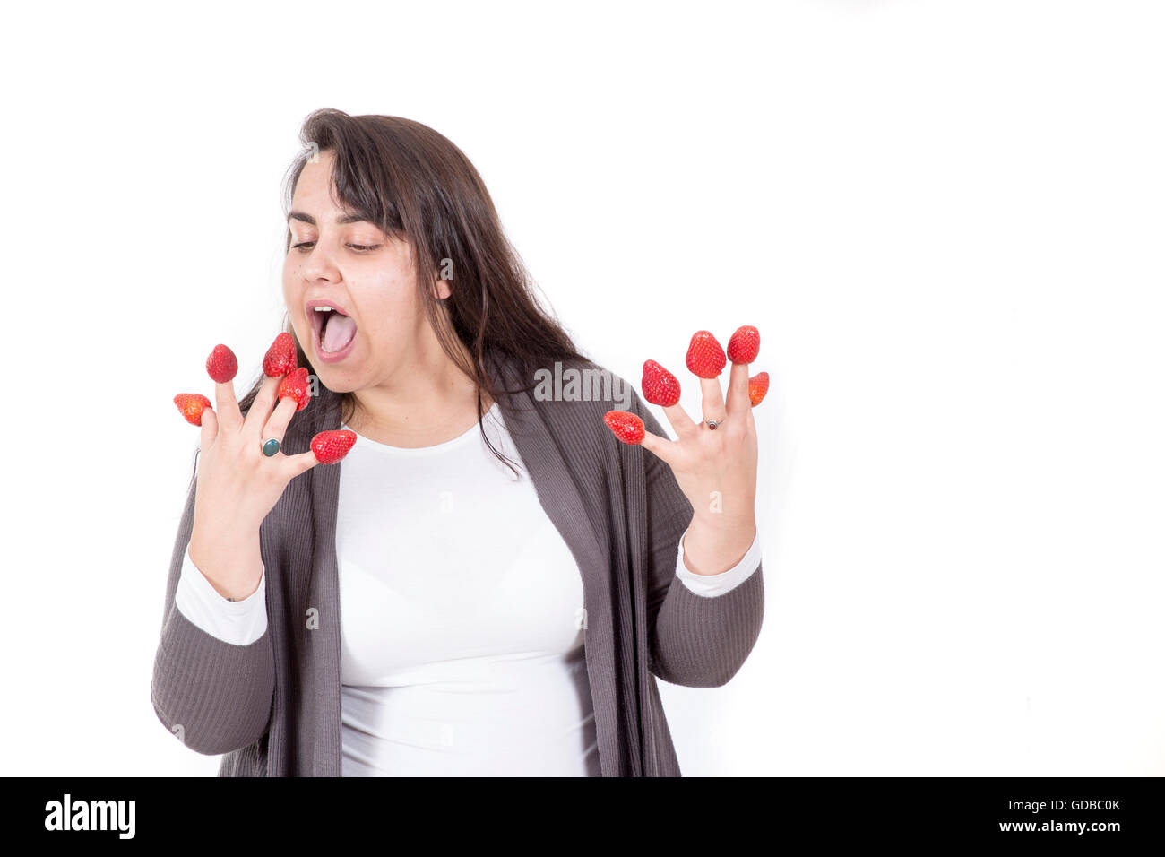 fat woman holding strawberries on fingers and look funny Stock Photo