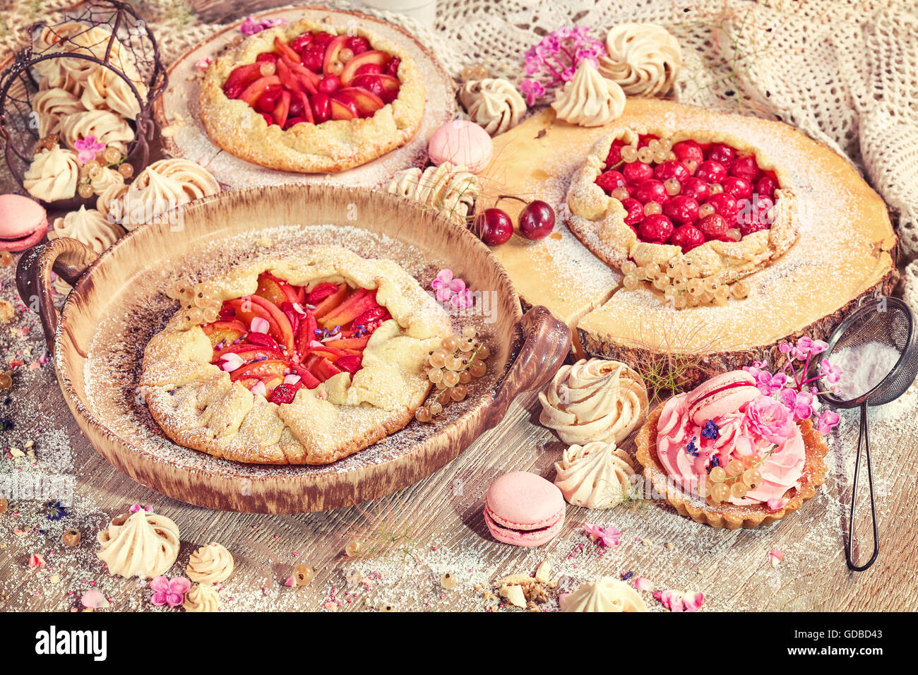 Rustic set of fruit tarts and meringues, homemade pastry, pastel colors. Stock Photo