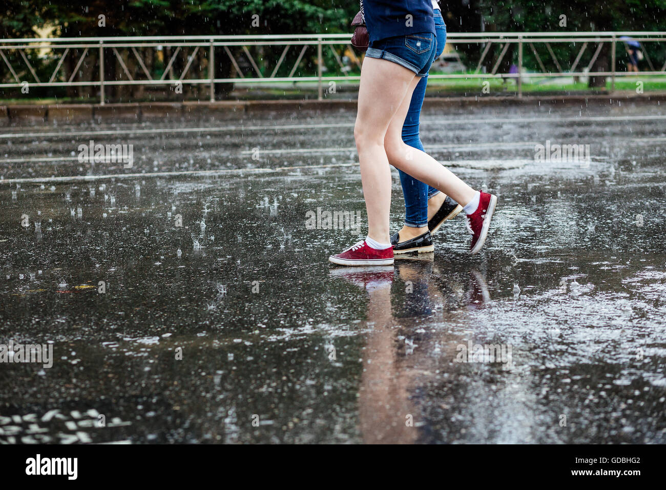 Two young women in boots crossing the street legs during heavy rain