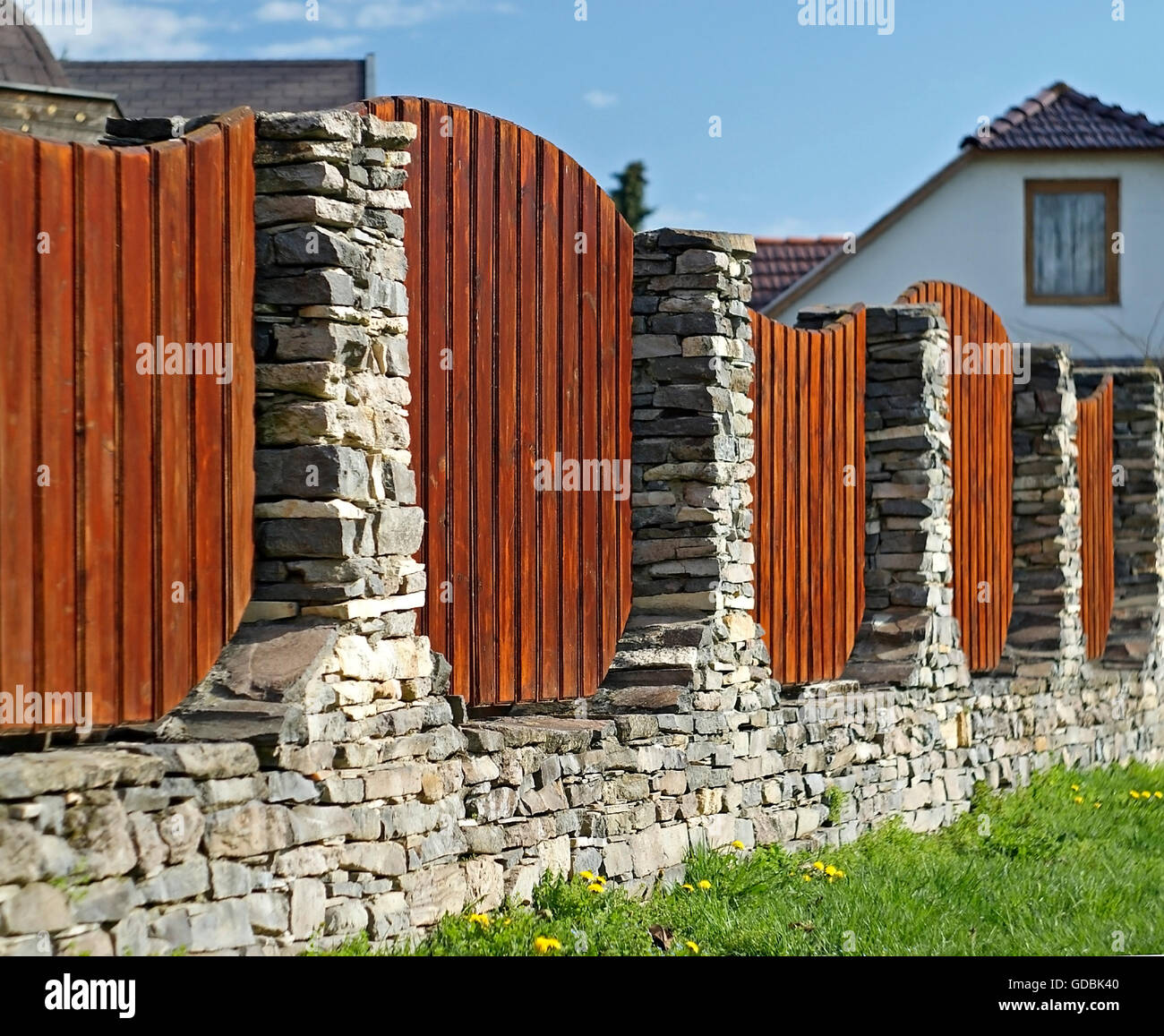 A beautiful lath fence with stone pillars. Stock Photo