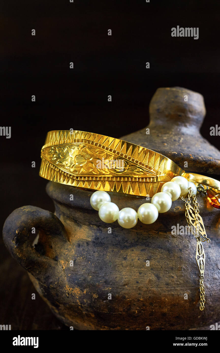 Clay pot full of jewelry on dark wooden background. Copy space Stock Photo