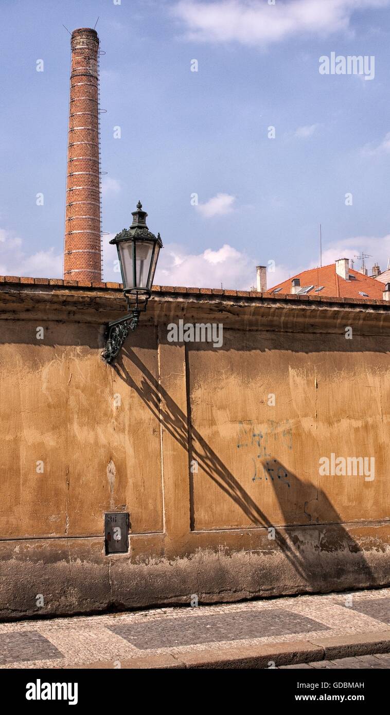 Mates - lamp and high funnel.Factory high funnel from bricks. Old - time lamp on the streets at background bricky chimney. Stree Stock Photo