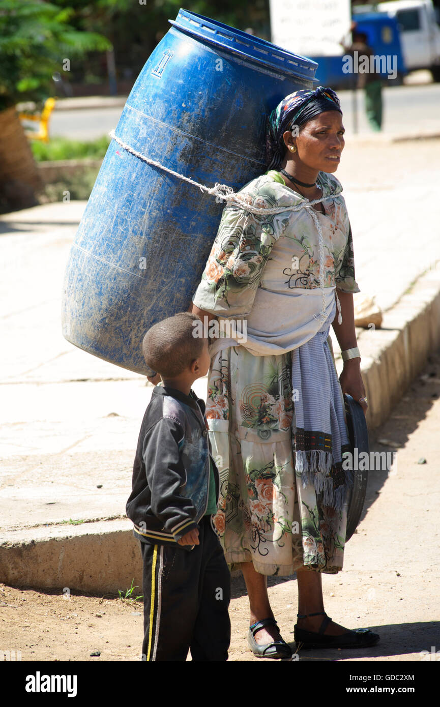 Ethiopian mother with son transporting large plastic barrel on her back. Wkro, Ethiopia Stock