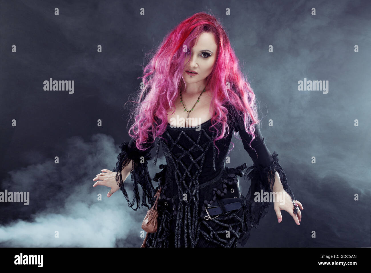 Halloween Witch creates magic. Attractive woman with red hair in