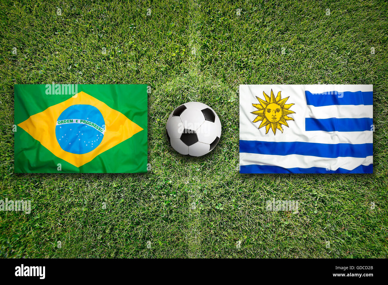 Brazil vs. Uruguay flags on green soccer field Stock Photo