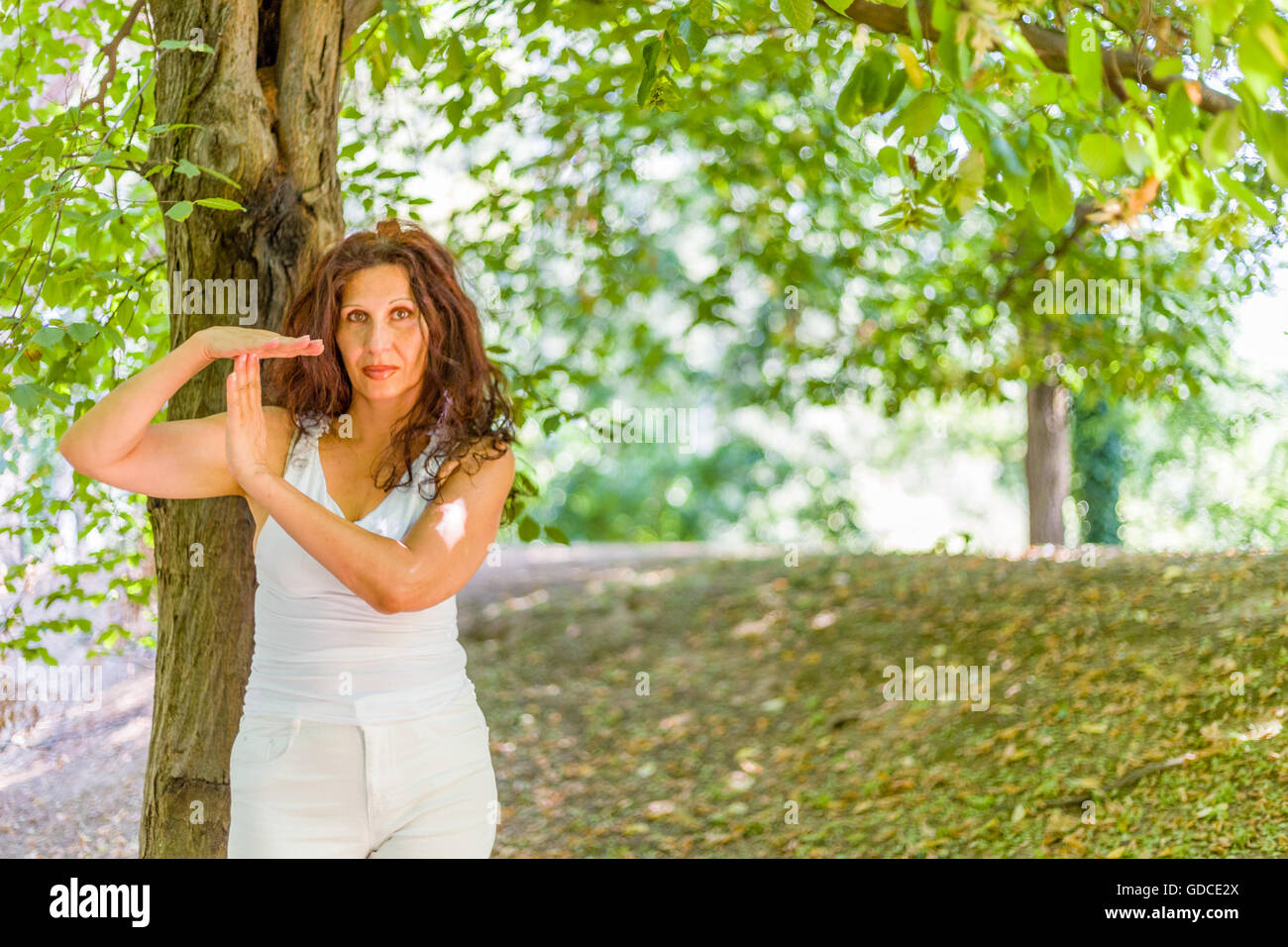Buxom mature woman in white dress showing time out gesture, over green background Stock Photo