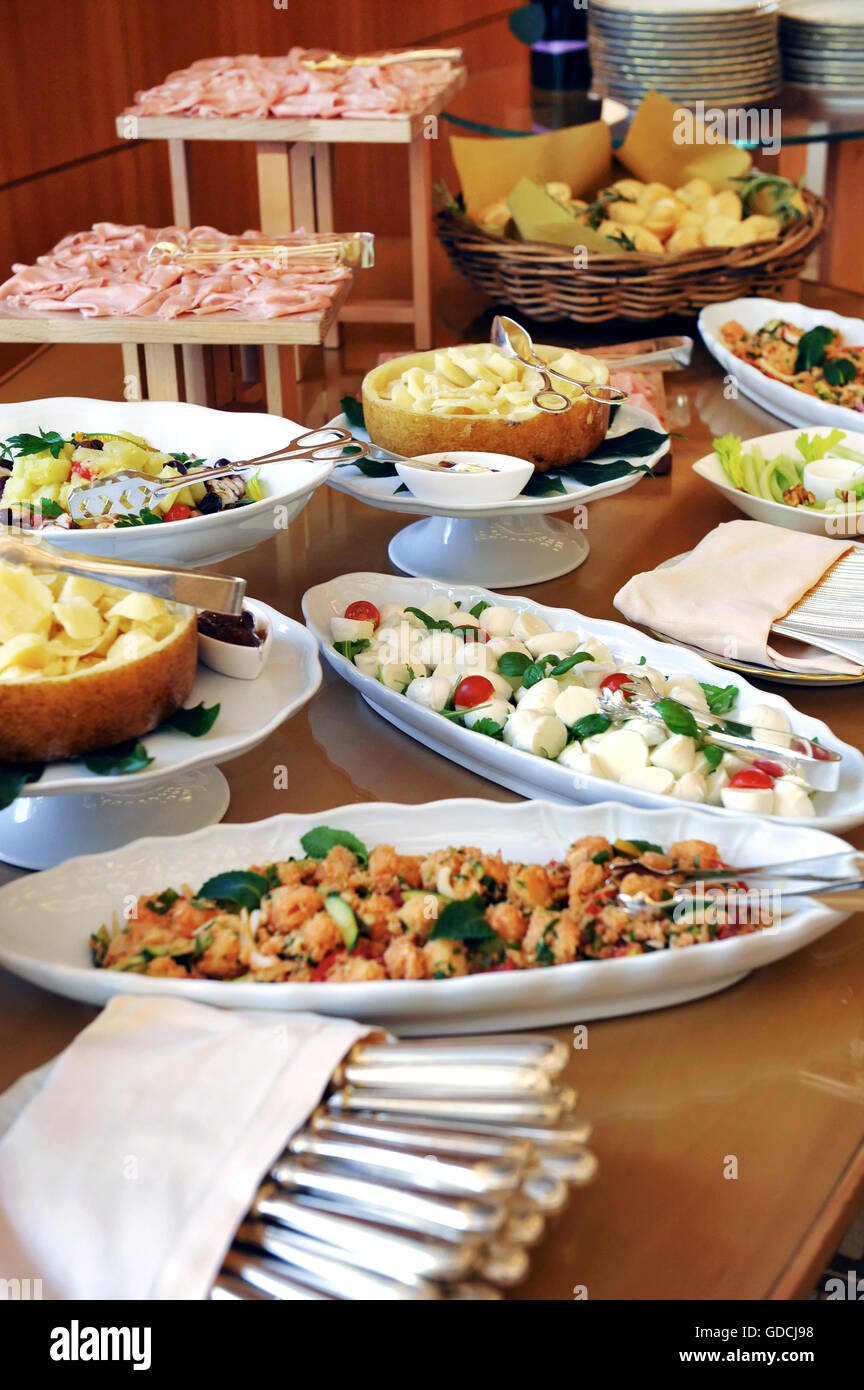 Assortment of food on a cold buffet at a hotel or catered event with sliced cold meats, salads and fish on display on individual Stock Photo