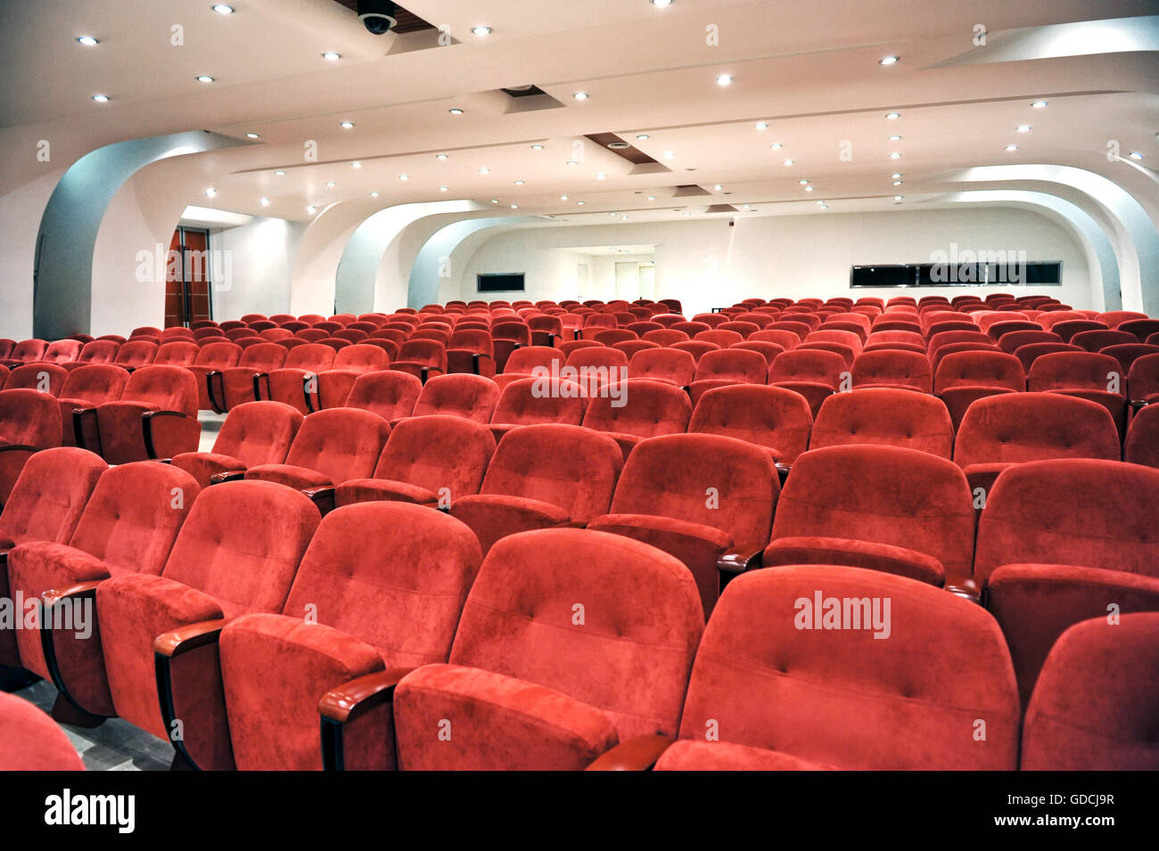 Rows of empty red seats for spectators in an auditorium, cinema or entertainment venue viewed close up Stock Photo