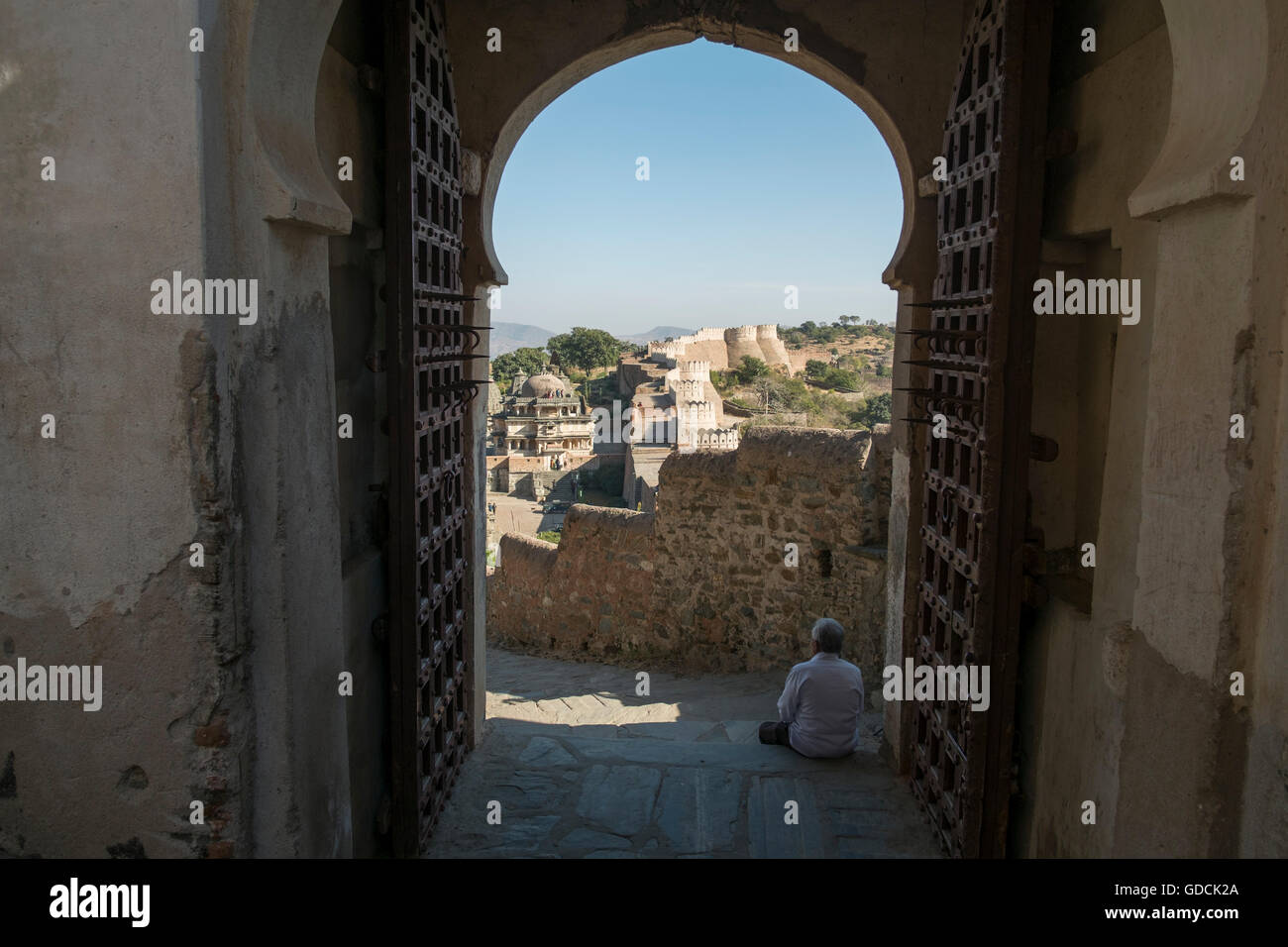 Man sitting in an elaborate gateway of Kumbhalgarh Fort, Rajasthan, India Stock Photo