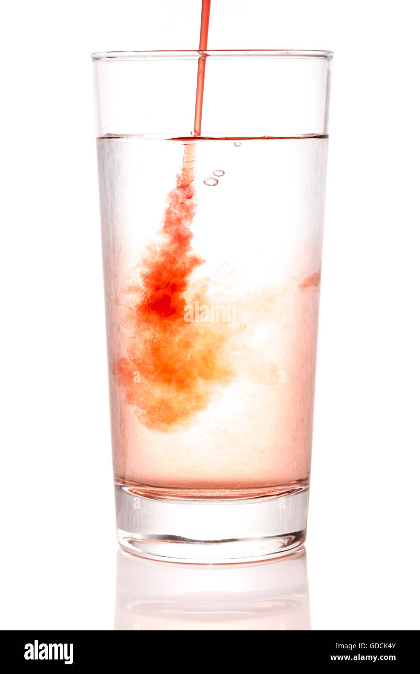 Pouring Squash into Glass of Water close up with a white background