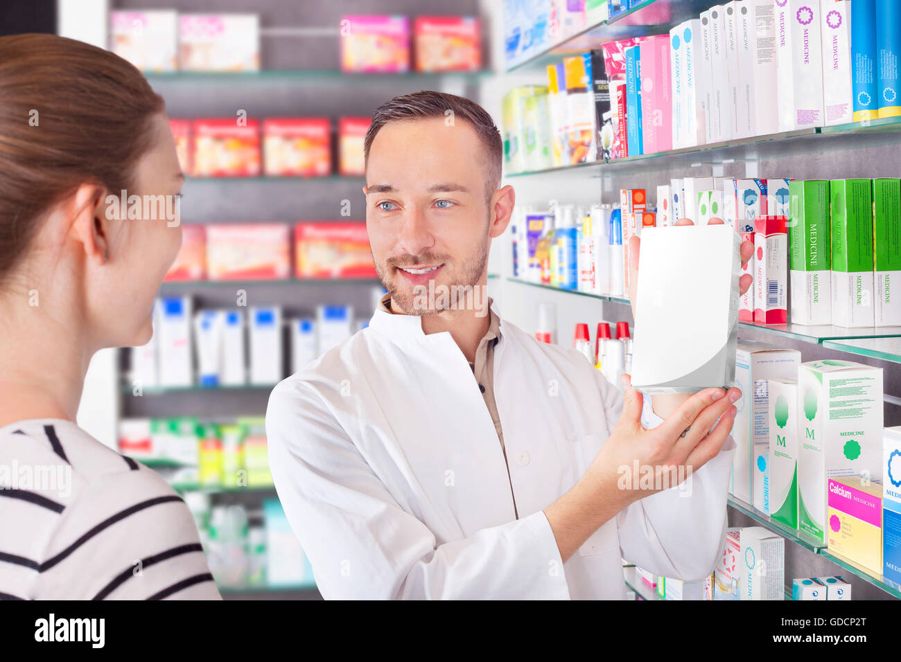 Pharmacist attending customer, showing product Stock Photo Alamy