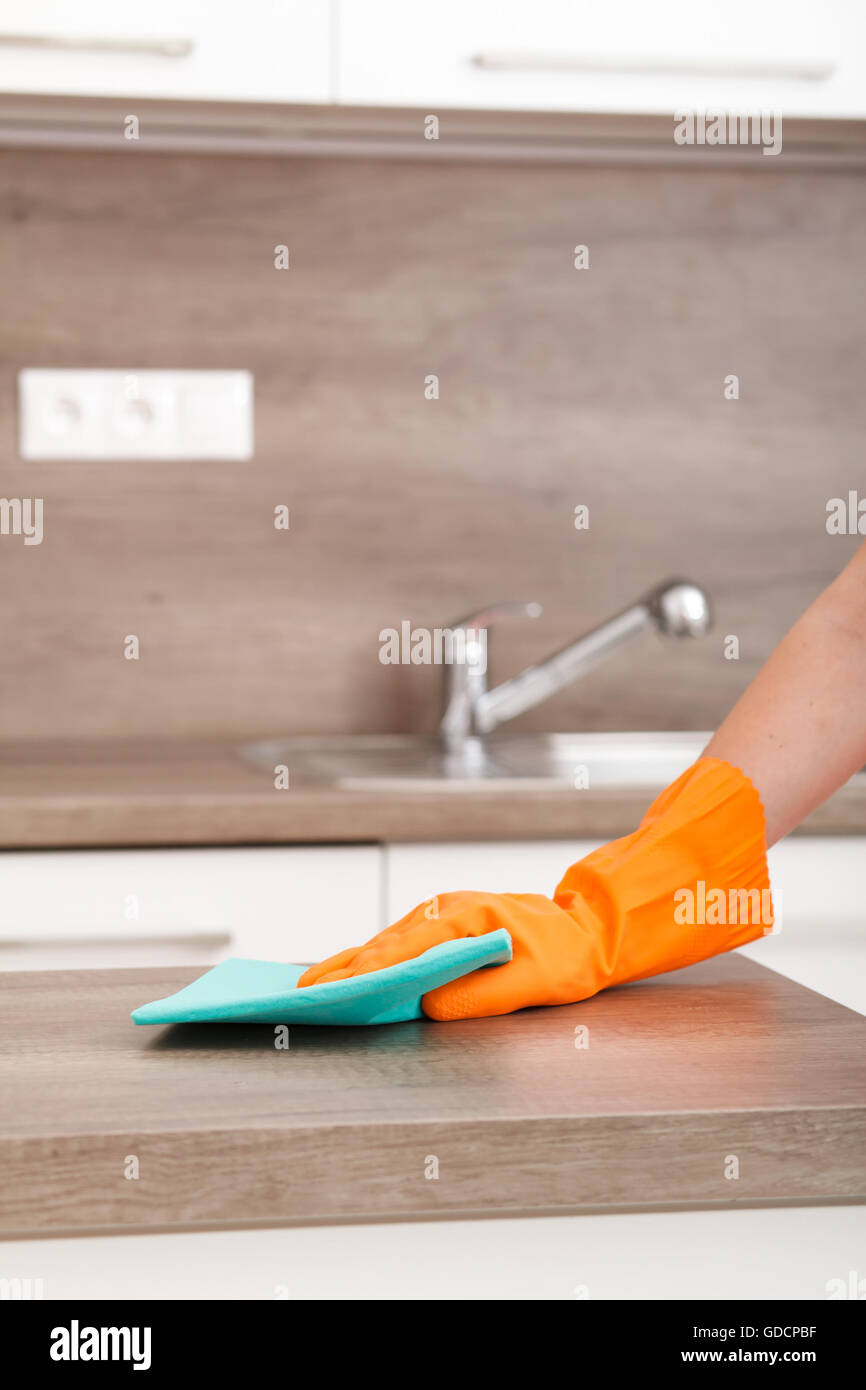 Hand in rubber glove cleans a new kitchen. Woman with housework