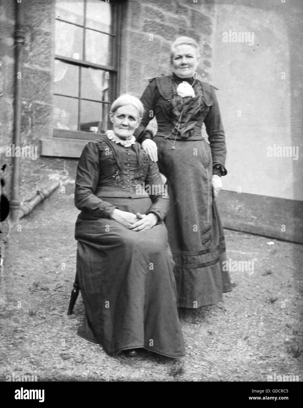 Two Victorian women dressed in formal full length black designs pose. Circa 1900. Photo by Tony Henshaw Stock Photo