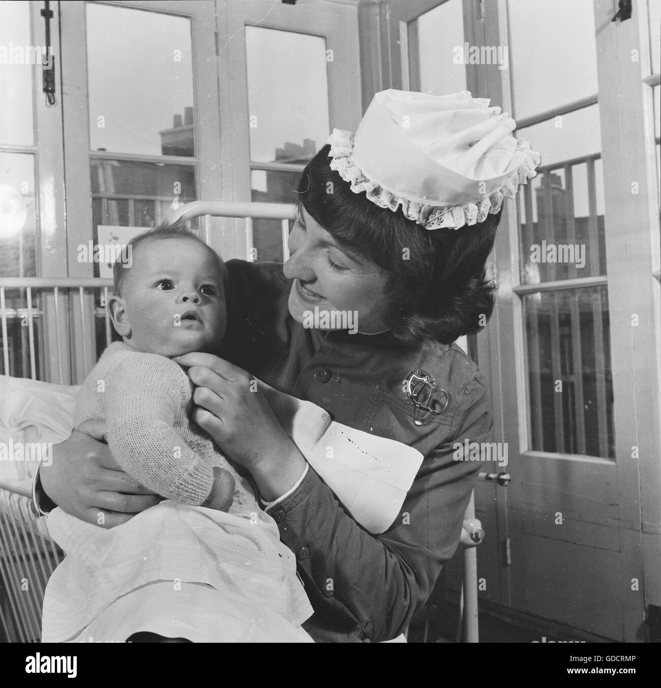 A Nurse / Sister holding a baby at a residential teaching hospital in Leicester c1962. Photograph by Tony Henshaw Stock Photo