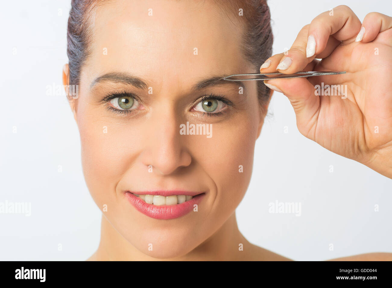 Close up of a woman plucking eyebrows with tweezers Stock Photo