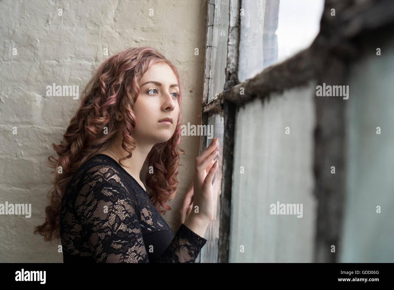 Sad woman standing by the window Stock Photo