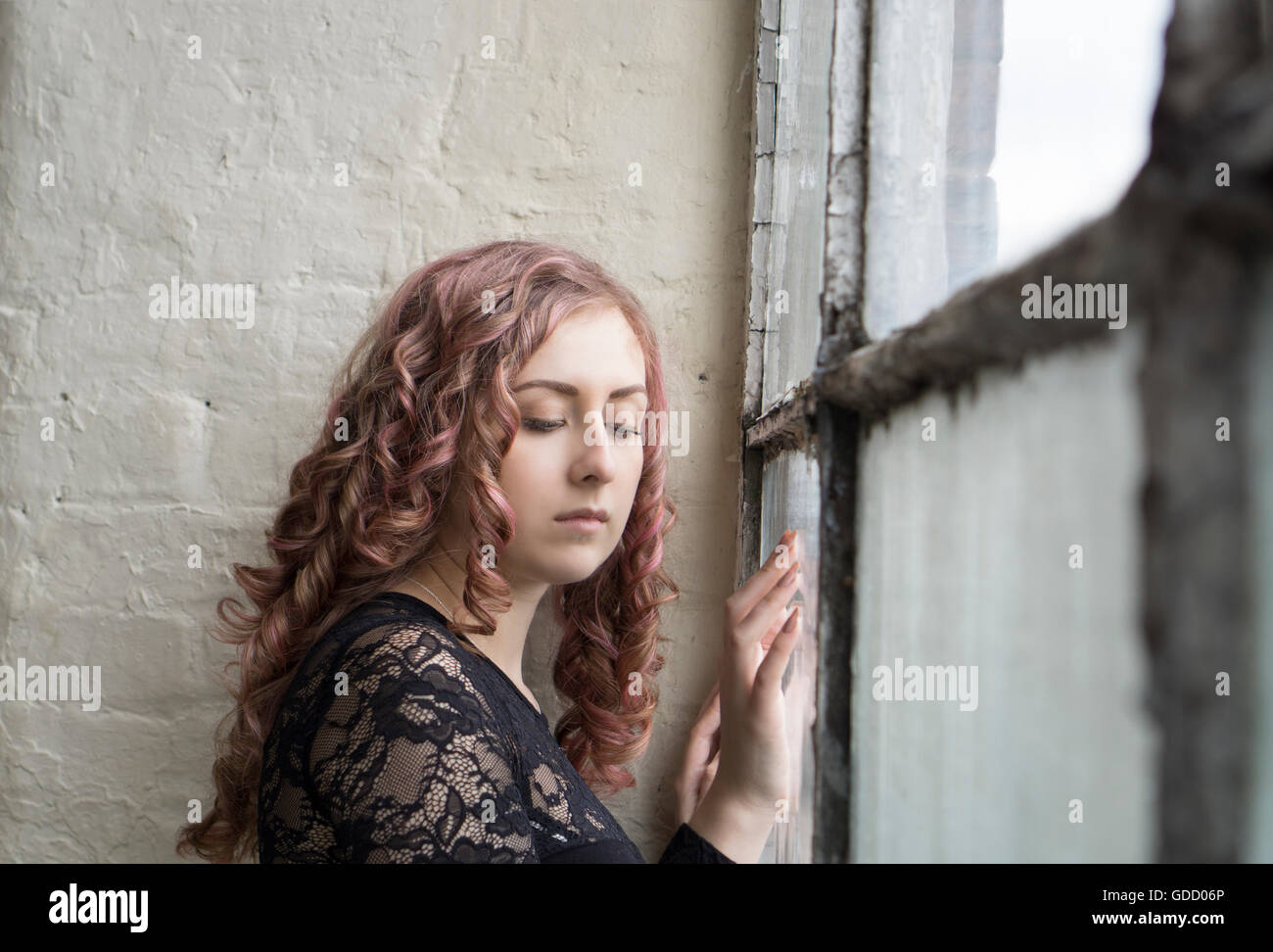 Sad woman standing by the window Stock Photo