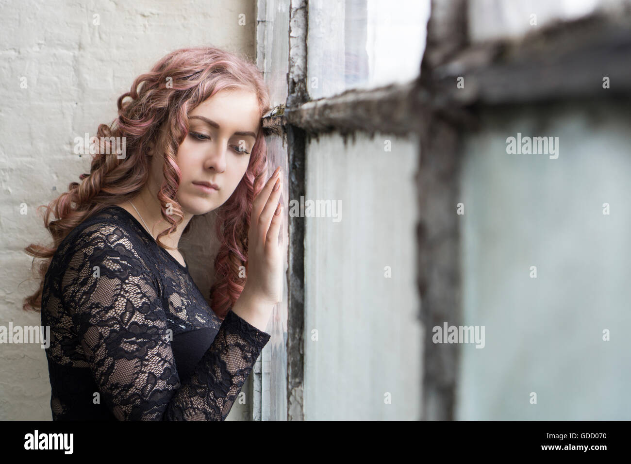 Sad woman standing by the window Stock Photo
